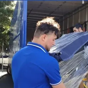 Two crew carrying a shrink-wrapped item into the back of a truck outside a Melbourne apartment block