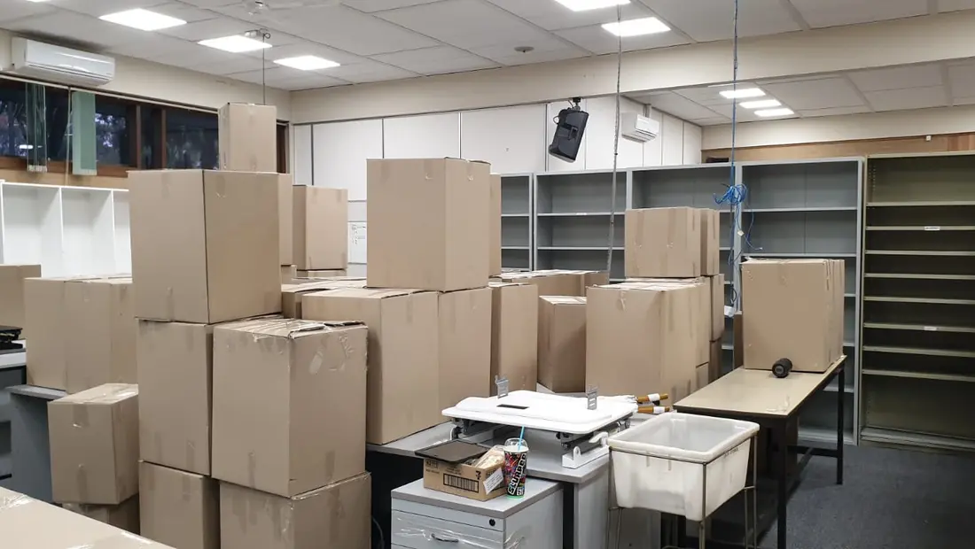 An office packed into moving cartons with shelving emptied, ready for relocation